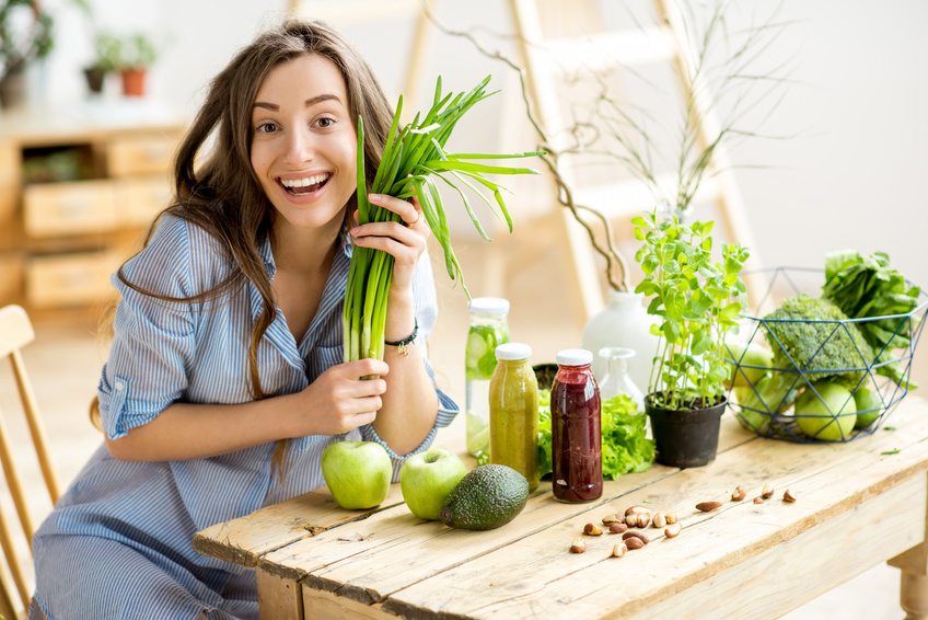 Portrait of a beautiful woman with fresh onion sitting on the table with healthy food indoors. Vegan meal concept | Foto: rh2010/ Fotolia